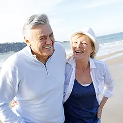 Active senior couple walking together on beach - healthy aging with anti-inflammatory curcumin supplements